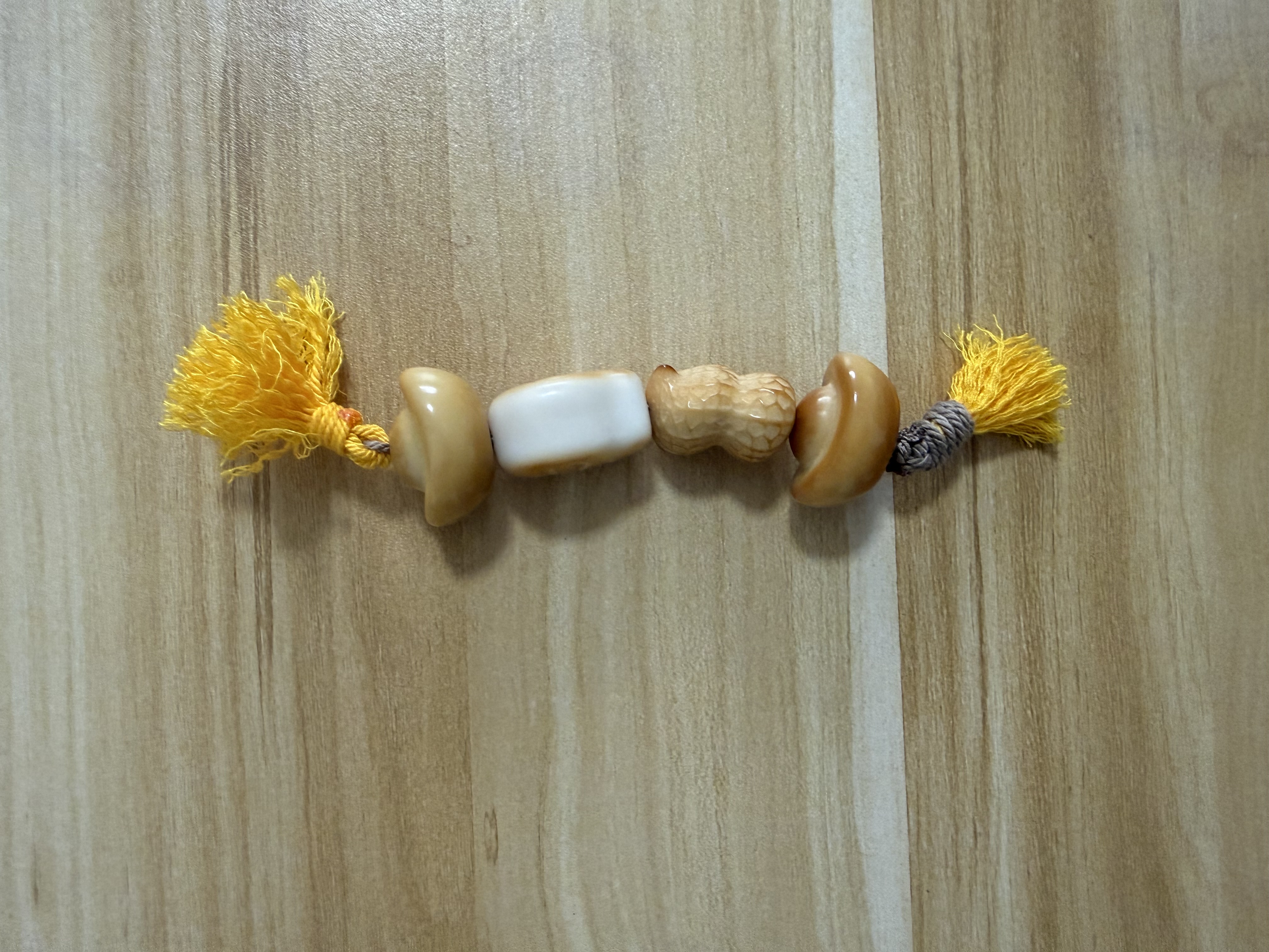 Gold and white shell beaded bracelet strand with yellow tassels