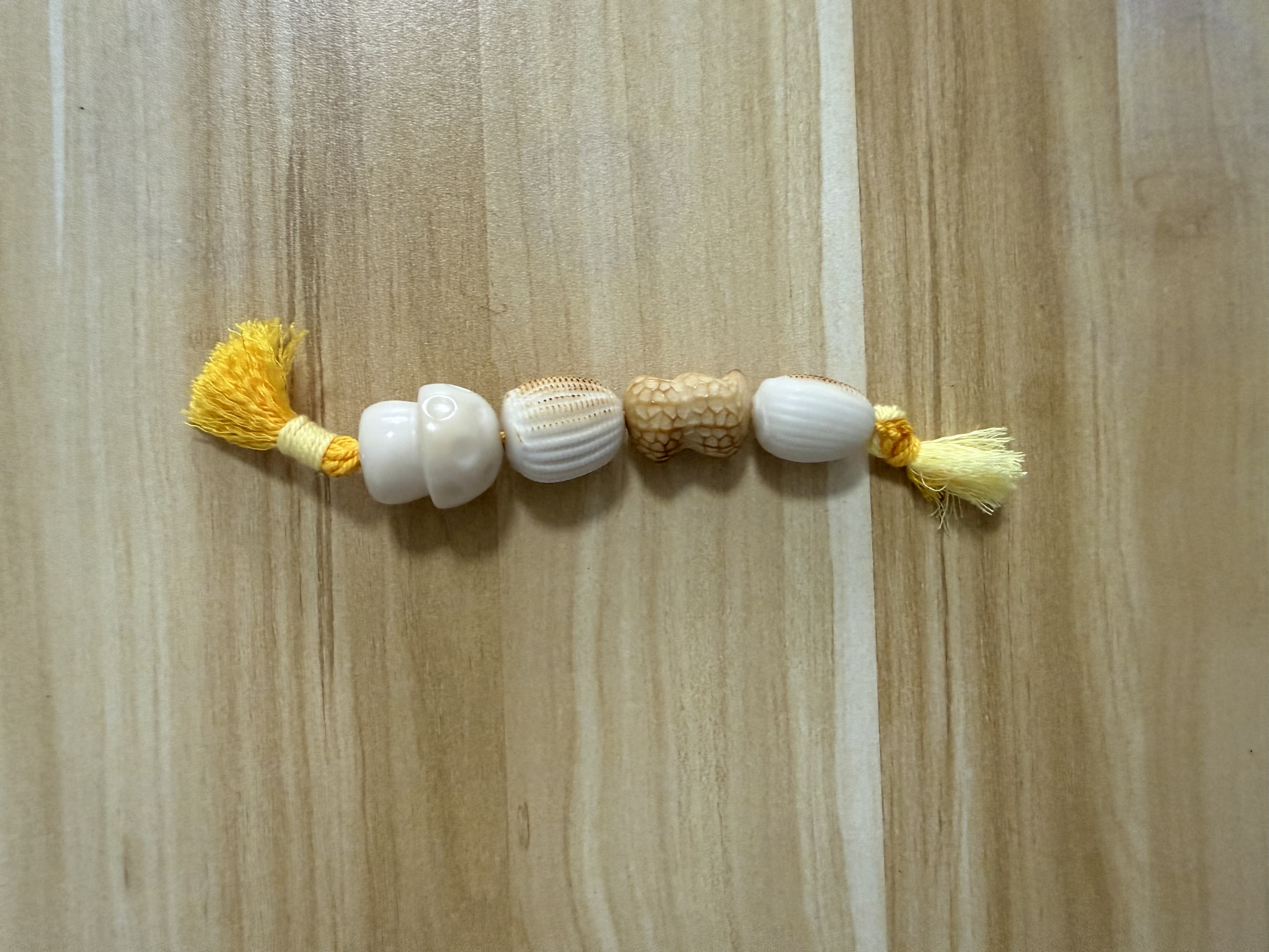 White roasted tagua nut beaded bracelet strand with yellow tassels