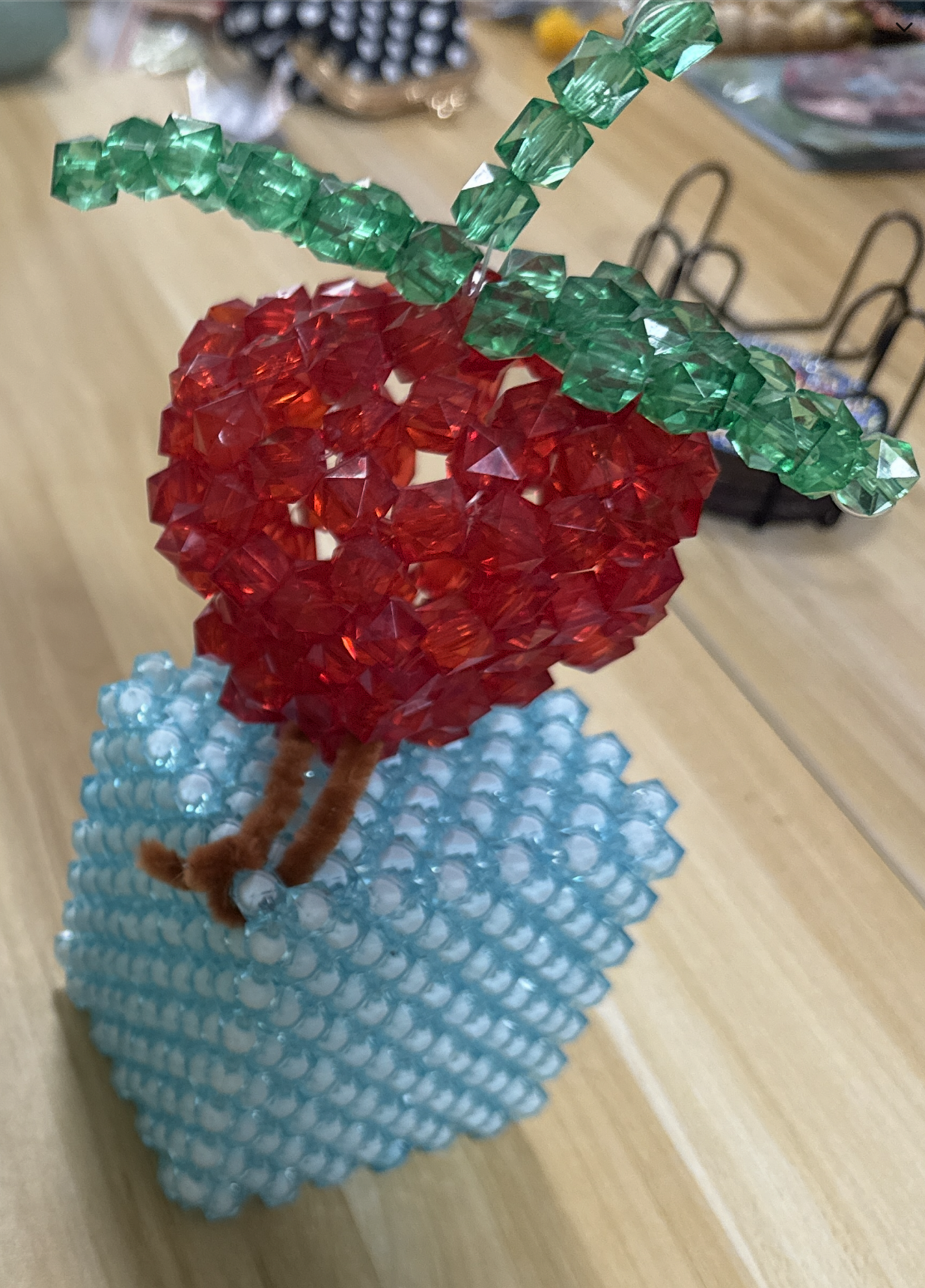 Red and green beaded fruit sculpture on a blue base