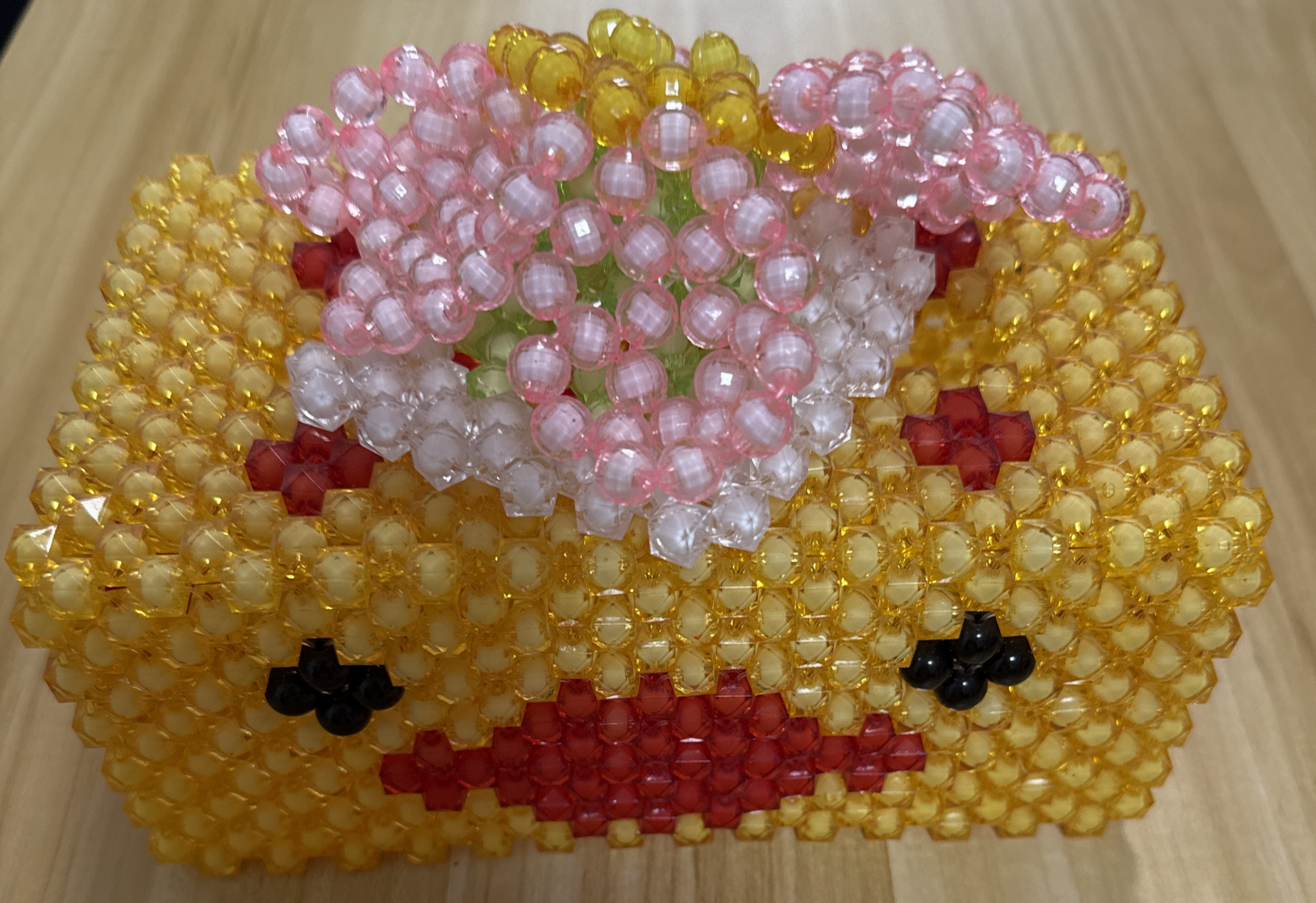 Yellow beaded basket sculpture with pink and white flowers